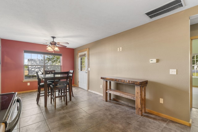 dining area with dark tile patterned floors and ceiling fan