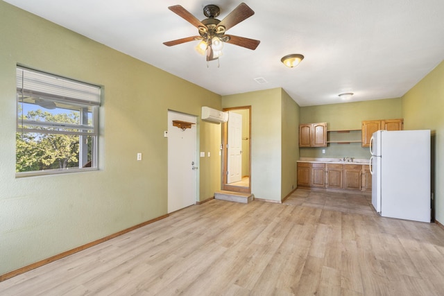 kitchen with an AC wall unit, white refrigerator, sink, and light hardwood / wood-style floors