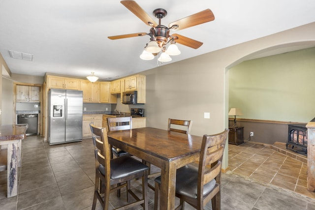 dining room with ceiling fan, sink, and a wood stove