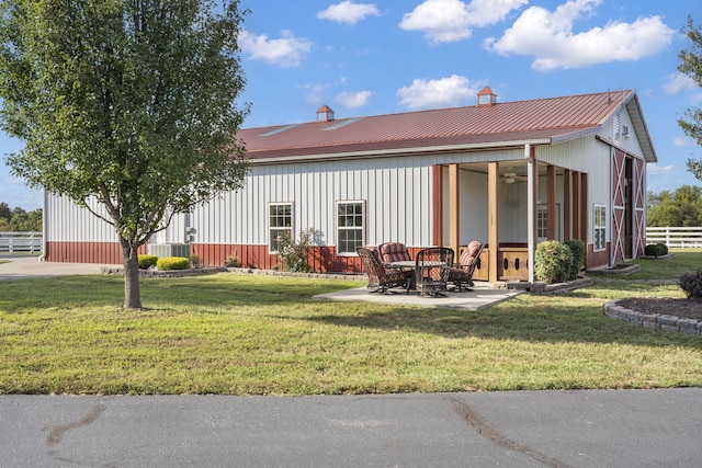 rear view of property with a ceiling fan, fence, a yard, a patio, and metal roof