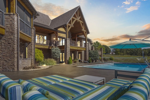 pool at dusk featuring an outdoor pool and a patio area