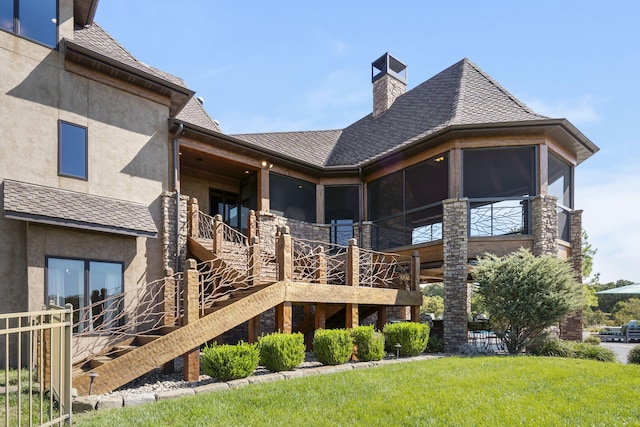 back of house with stucco siding, a chimney, roof with shingles, and a yard