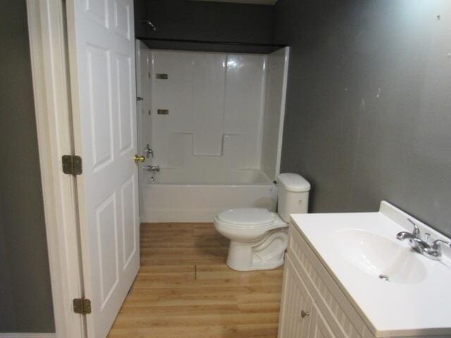 full bathroom featuring hardwood / wood-style floors, shower / washtub combination, vanity, and toilet