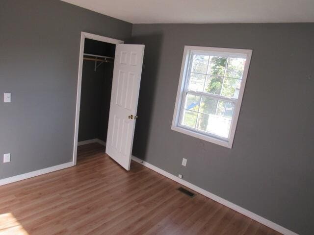 unfurnished bedroom featuring lofted ceiling, a closet, and dark hardwood / wood-style floors