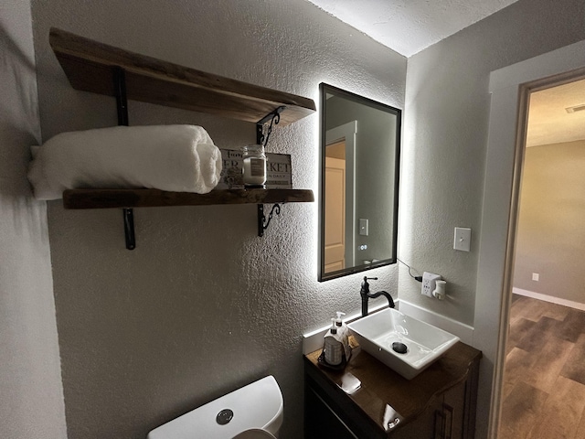 bathroom with toilet, vanity, and hardwood / wood-style flooring