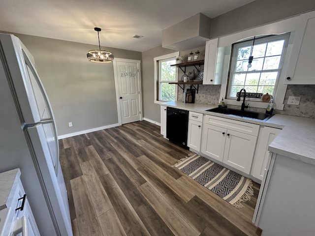 kitchen featuring dishwasher, hanging light fixtures, sink, white fridge, and white cabinetry