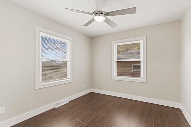 empty room with ceiling fan, plenty of natural light, and dark hardwood / wood-style flooring