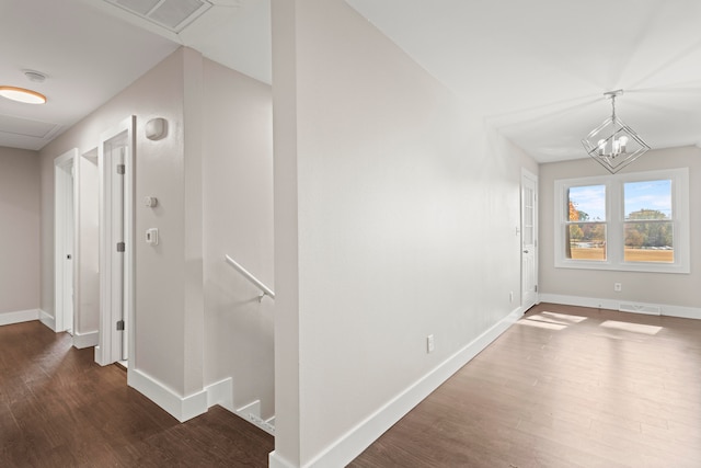 hall with an inviting chandelier and dark wood-type flooring