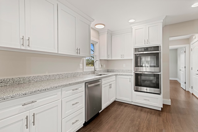 kitchen featuring sink, white cabinetry, stainless steel appliances, dark wood-type flooring, and light stone counters