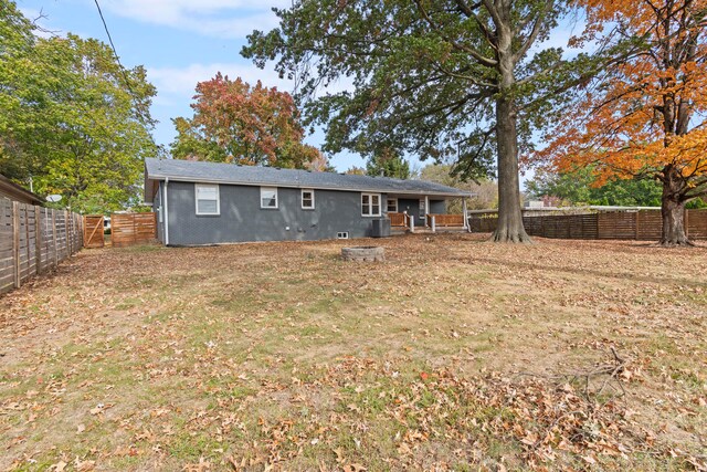 back of property with central AC and a yard