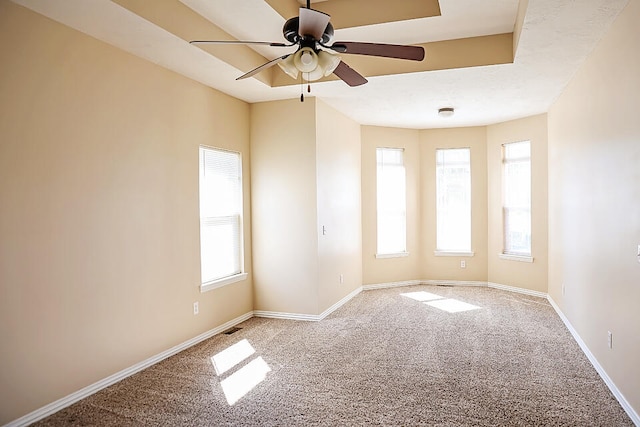 spare room featuring ceiling fan, a wealth of natural light, and carpet