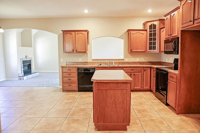 kitchen featuring light tile patterned floors, sink, a wood stove, black appliances, and a center island