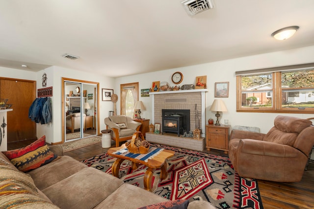 living room with a brick fireplace and dark hardwood / wood-style flooring