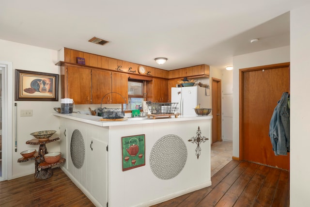 kitchen with kitchen peninsula, decorative backsplash, white refrigerator, and dark hardwood / wood-style floors