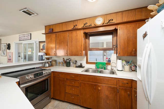 kitchen featuring stainless steel electric stove, sink, light tile patterned floors, and white refrigerator with ice dispenser