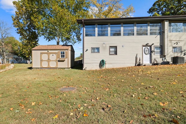 back of house with a storage shed, a lawn, and central AC