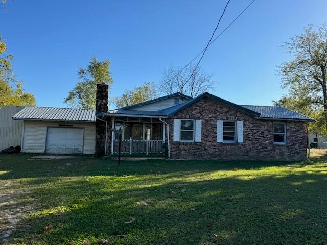 view of front of property featuring a porch, a front yard, and a garage