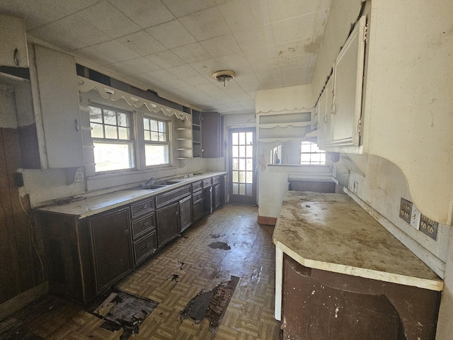 kitchen featuring a sink, light countertops, dark brown cabinets, and open shelves