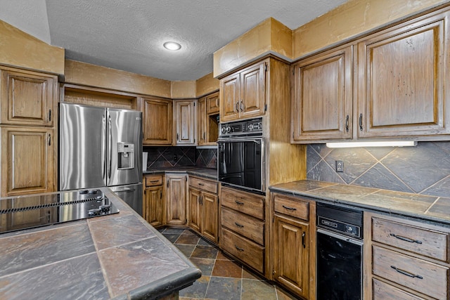 kitchen featuring a textured ceiling, tile countertops, tasteful backsplash, and black appliances