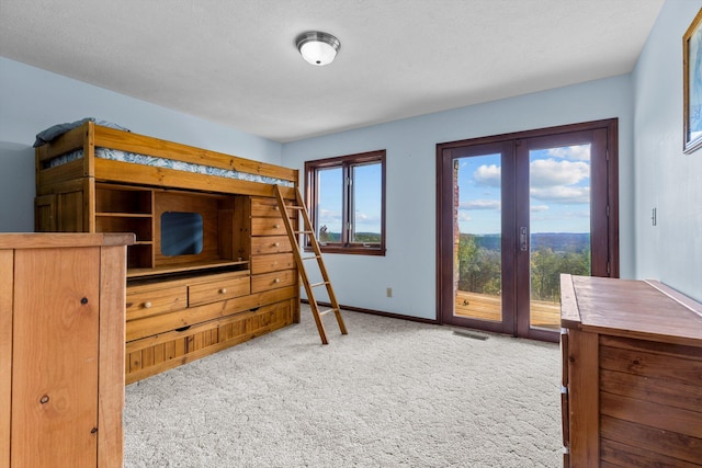 bedroom with light colored carpet, a textured ceiling, access to exterior, and multiple windows