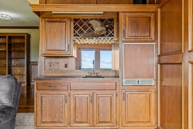 kitchen with hardwood / wood-style floors, crown molding, and sink