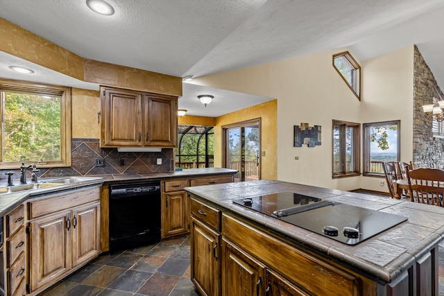 kitchen with black appliances, a center island, sink, tile counters, and a textured ceiling