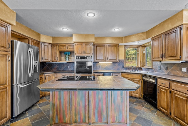 kitchen featuring sink, a textured ceiling, black appliances, tile countertops, and a center island