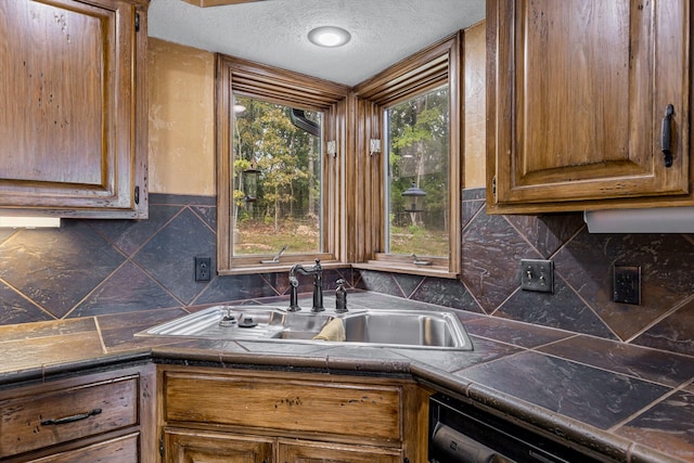 kitchen featuring a healthy amount of sunlight, sink, tile countertops, and a textured ceiling