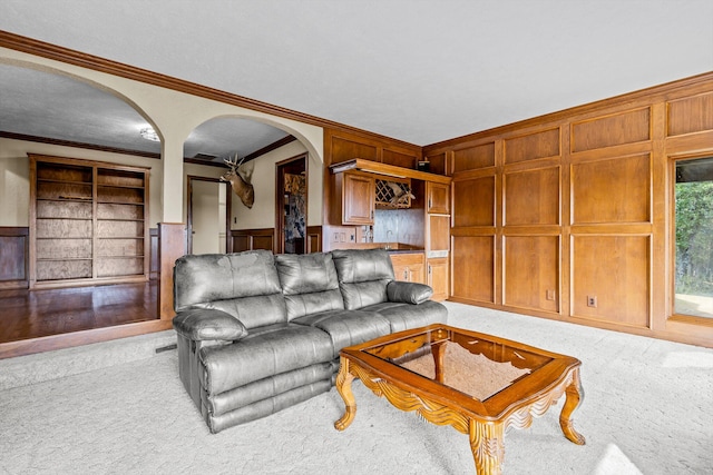 living room featuring built in features, ornamental molding, and light colored carpet