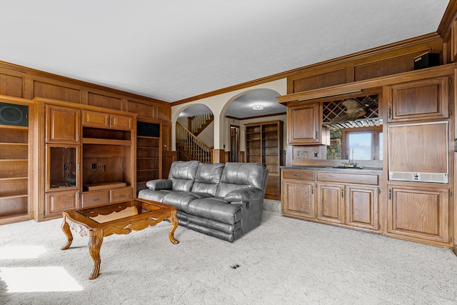 living room with light carpet, sink, crown molding, and wood walls