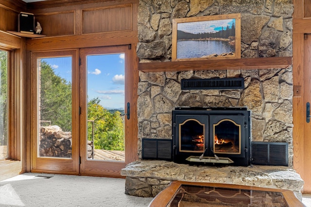 interior space featuring carpet floors, wood walls, and a stone fireplace