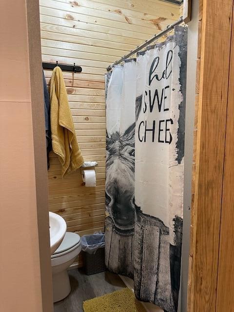 bathroom with toilet, wood walls, walk in shower, and hardwood / wood-style floors