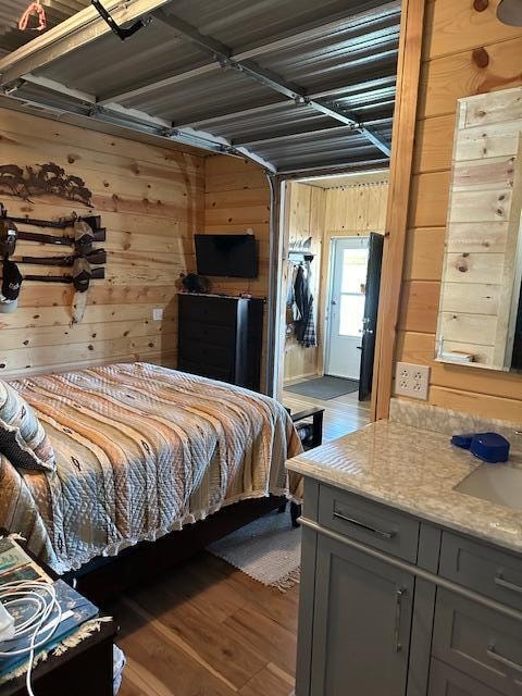 bedroom featuring dark wood-type flooring, sink, and wooden walls