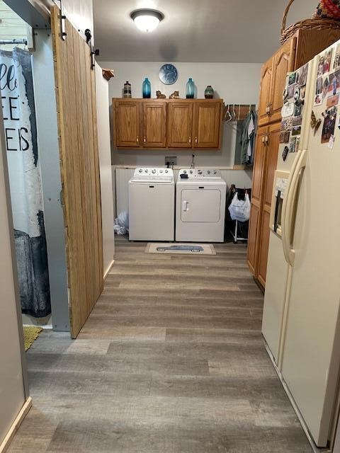 washroom featuring light hardwood / wood-style floors, cabinets, washer and clothes dryer, and a barn door