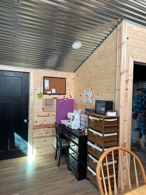 office area with vaulted ceiling, wood-type flooring, and wood walls