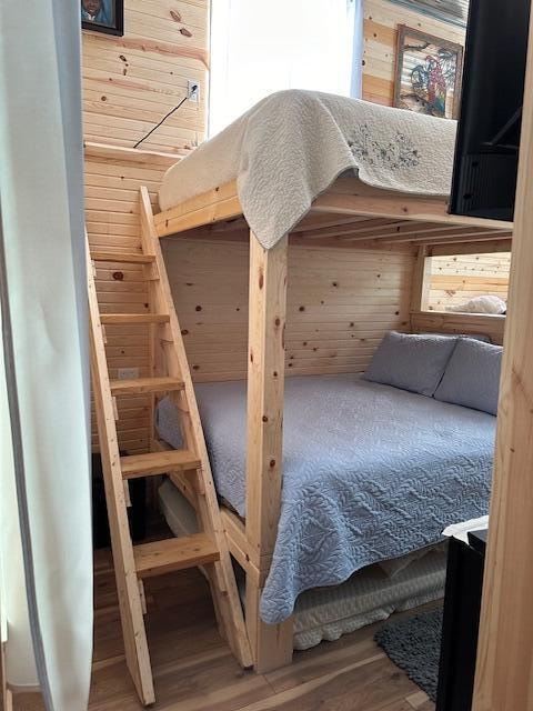 bedroom with hardwood / wood-style floors and wooden walls