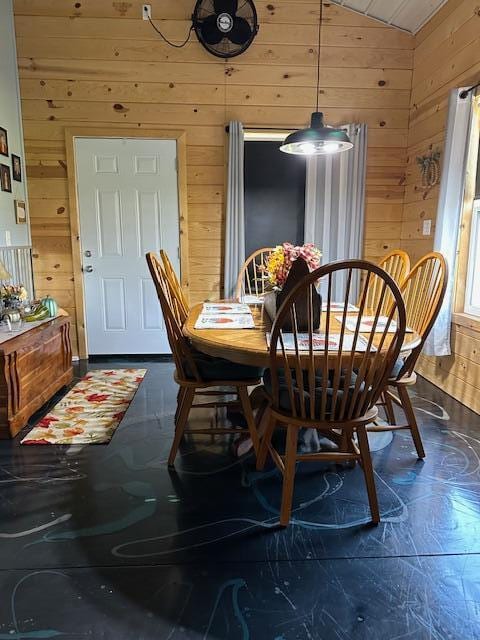 dining area featuring vaulted ceiling and wood walls