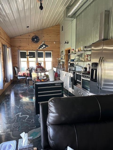 kitchen featuring lofted ceiling, wooden walls, hanging light fixtures, and stainless steel appliances