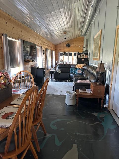 dining space with lofted ceiling and wooden walls