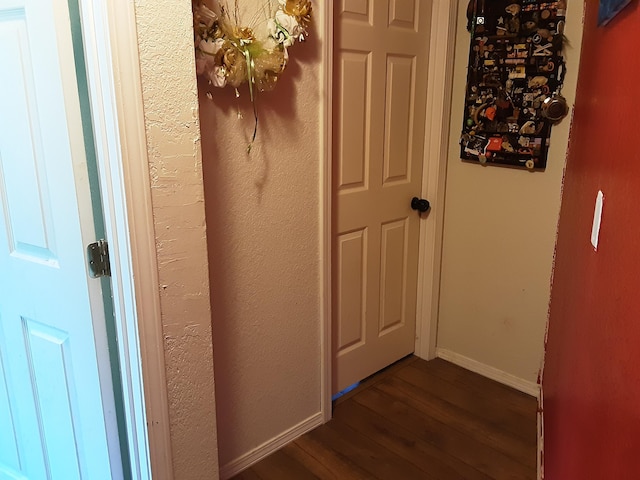 interior space featuring baseboards and dark wood-style flooring