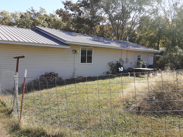 view of property exterior featuring metal roof and fence