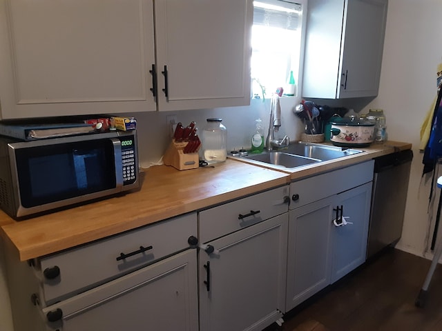 kitchen featuring gray cabinetry, sink, dark hardwood / wood-style floors, butcher block countertops, and stainless steel appliances