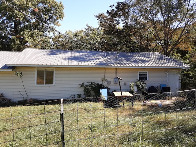 view of side of home featuring metal roof and fence