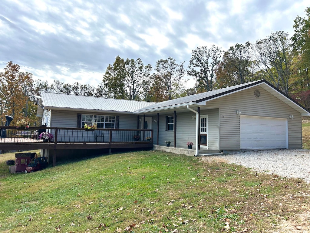 single story home with a wooden deck, a front yard, and a garage