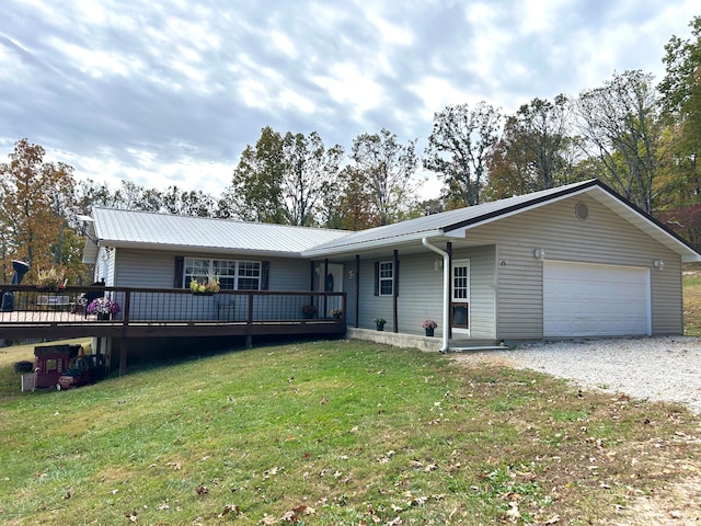 single story home with a wooden deck, a front yard, and a garage