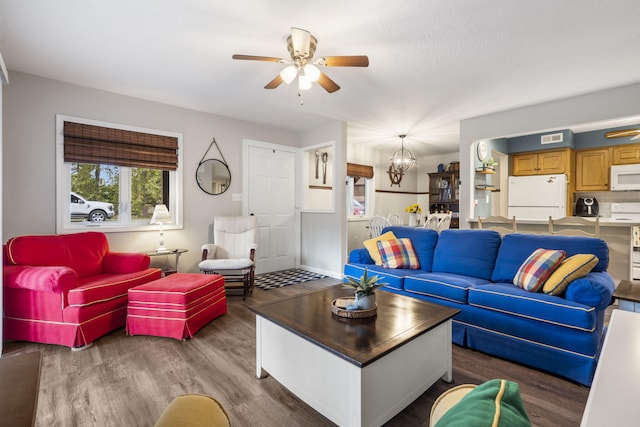 living room featuring dark wood-type flooring and ceiling fan with notable chandelier