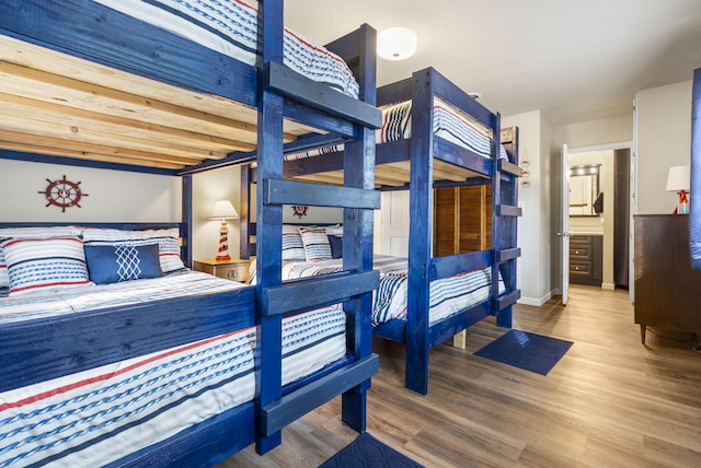 bedroom with connected bathroom and wood-type flooring