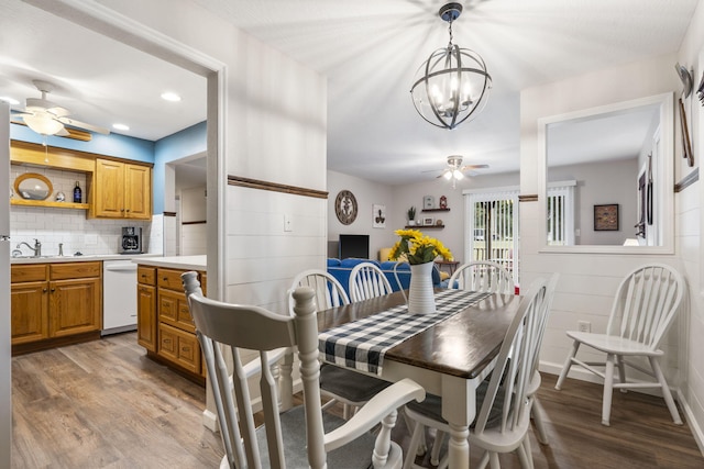 dining area featuring sink, dark hardwood / wood-style flooring, and ceiling fan with notable chandelier