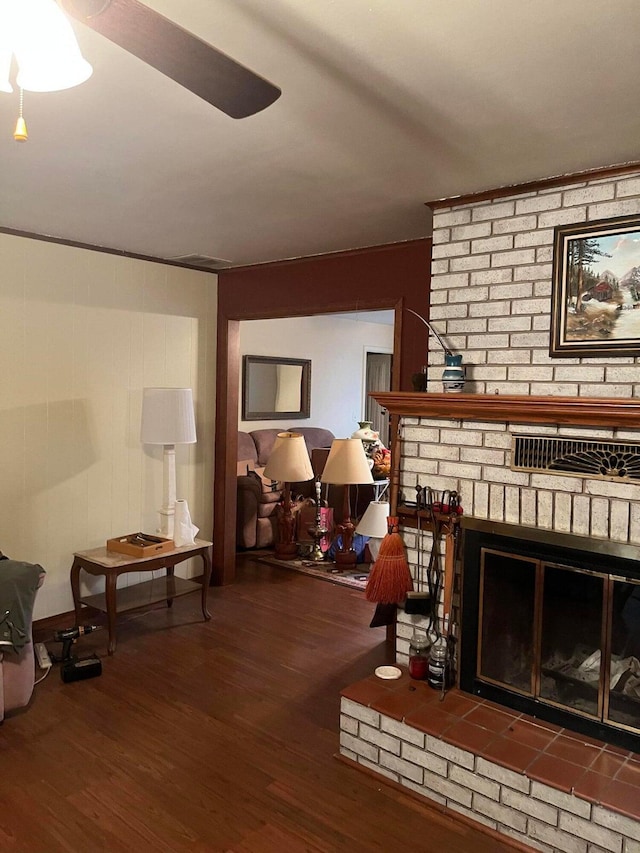 living room with dark wood-type flooring, ceiling fan, and a brick fireplace