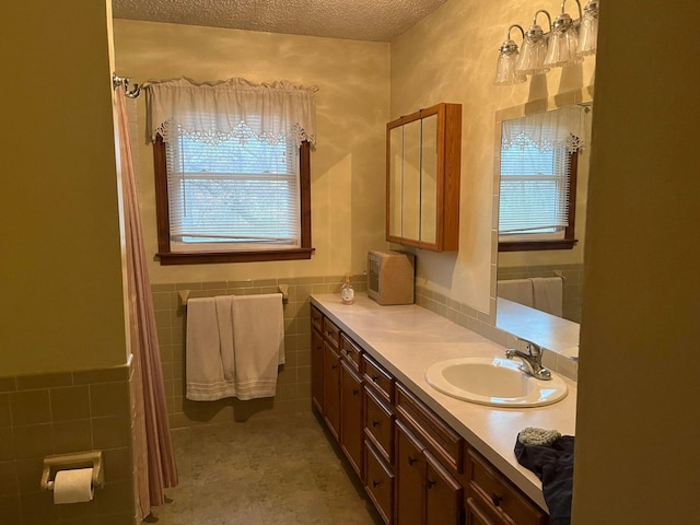 bathroom with tile walls, vanity, and a textured ceiling